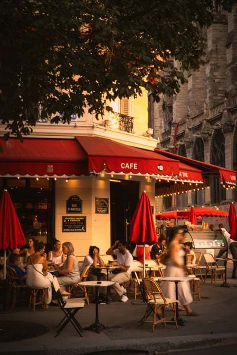 Terrasse de café parisien au coucher du soleil, store rouge et lumière dorée — l'ambiance détente qui inspire l'univers Moody CBD. Moments de pause et art de vivre à la française