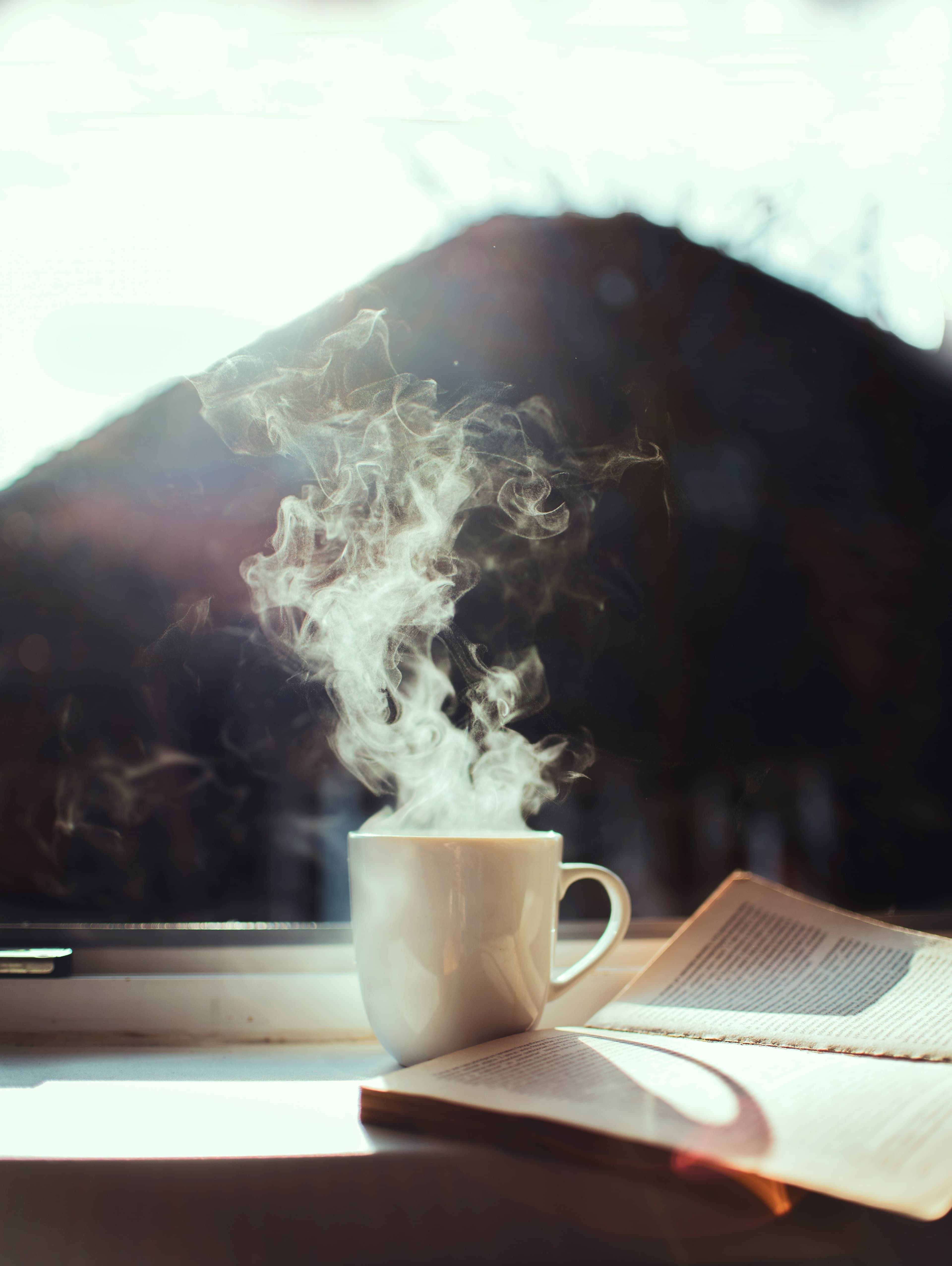 Tasse de café et livre sur un rebord de fenêtre au matin — rituel énergie sans café excessif