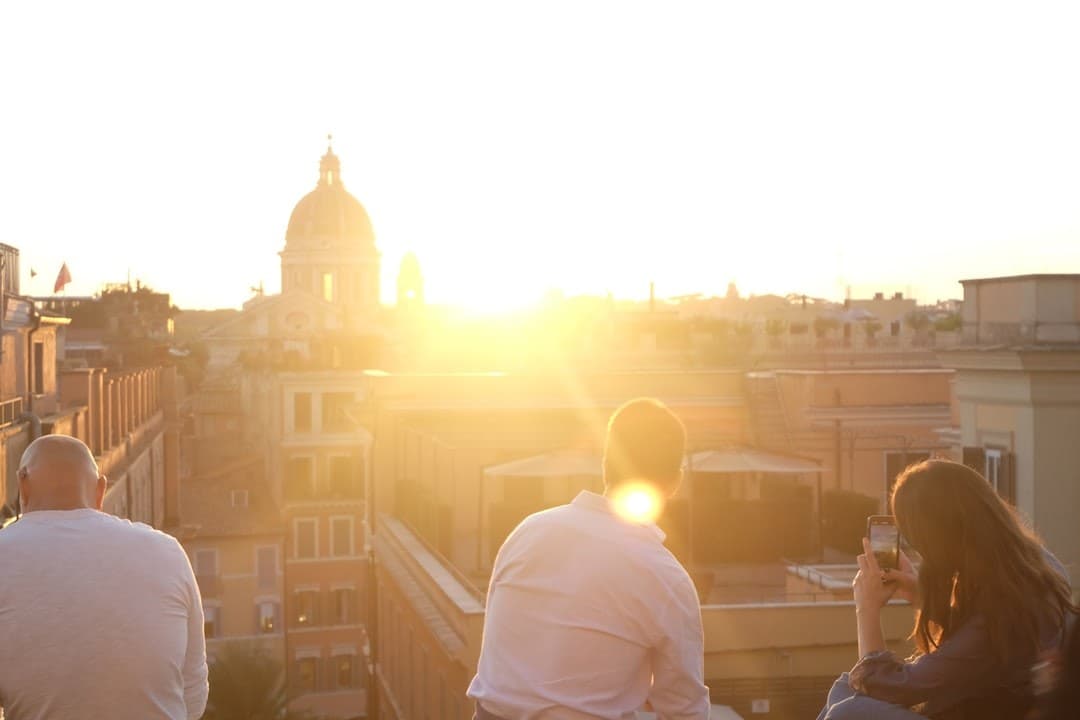 People watch sunset over city buildings